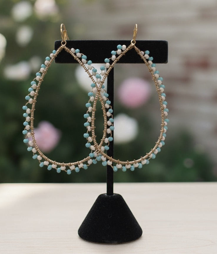 Pair of beaded earrings on a black stand with a blurred background
