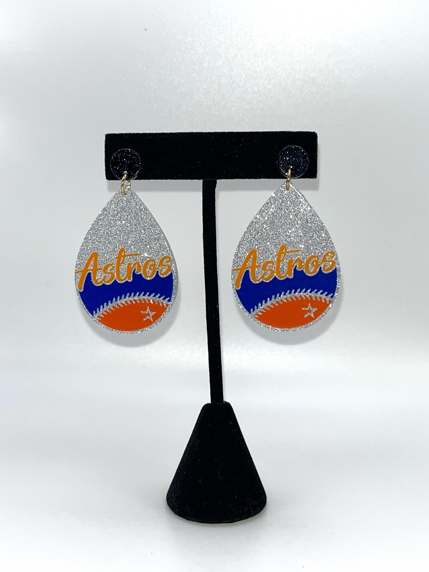 Teardrop-shaped earrings with 'Astros' text on a black stand against a white background