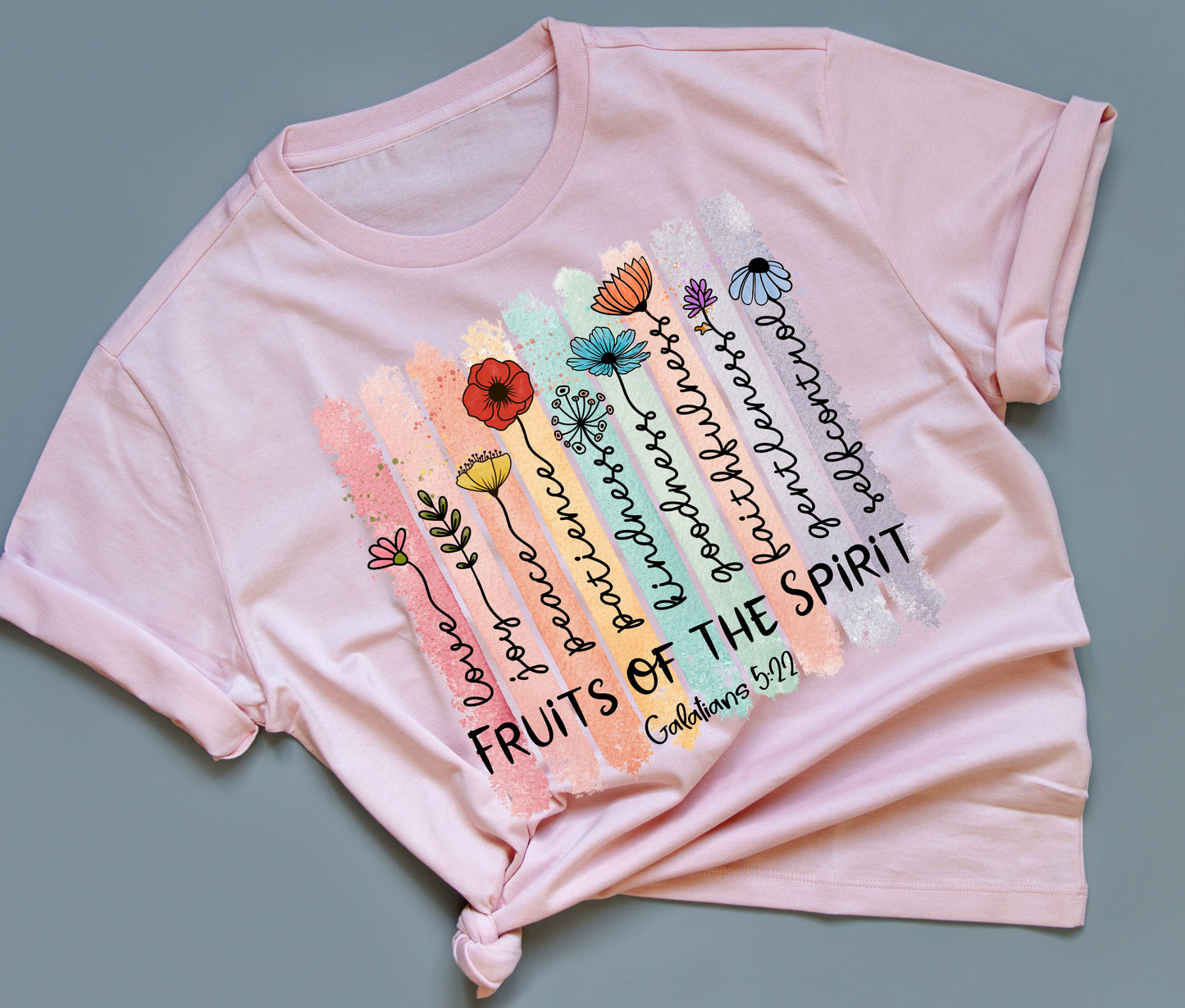 Pink t-shirt with colorful floral design and text on a gray background