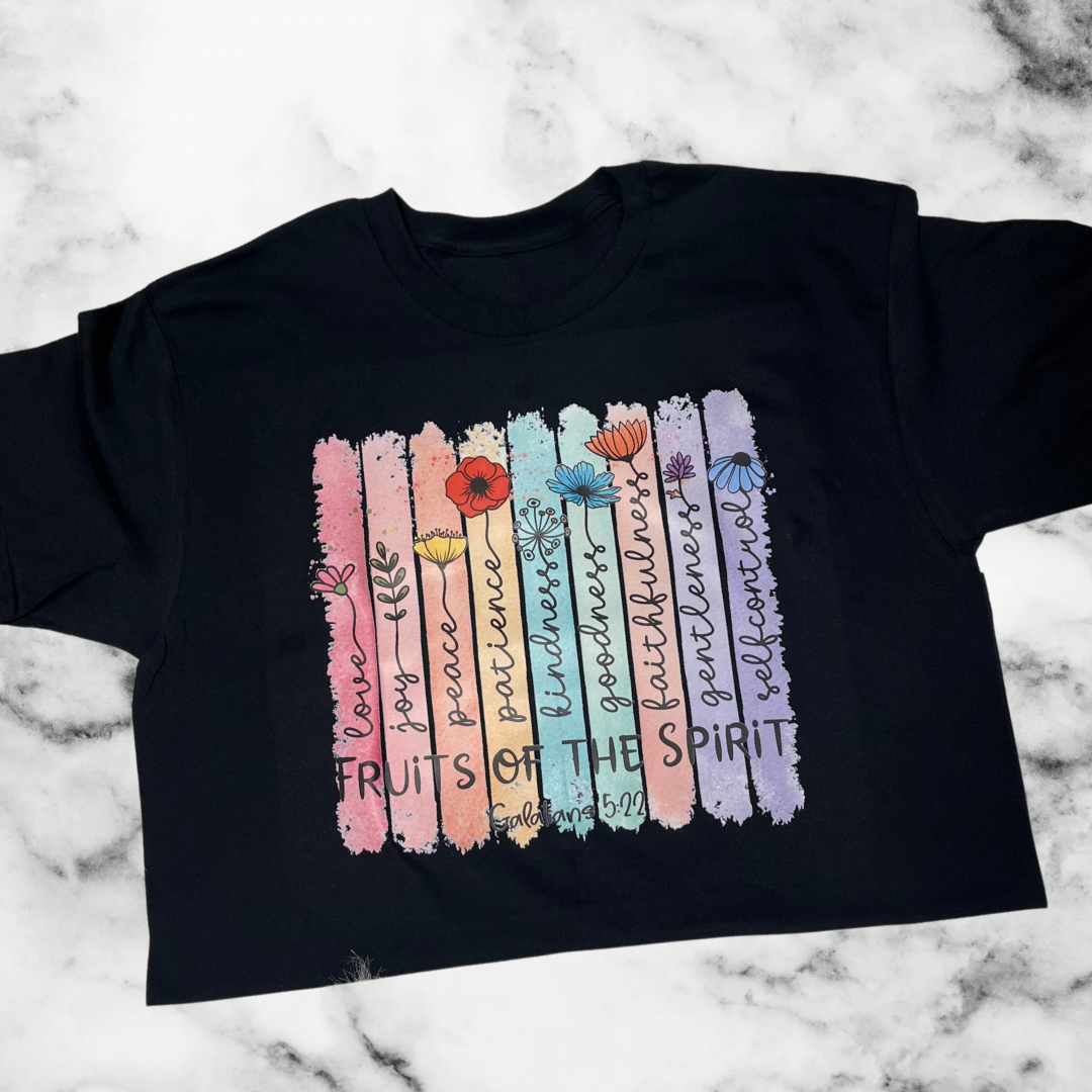 Black t-shirt with colorful 'Fruits of the Spirit' design on a marble background