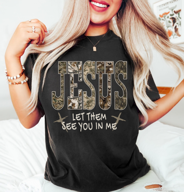 Person wearing a black t-shirt with 'Jesus Let Them See You In Me' text design.