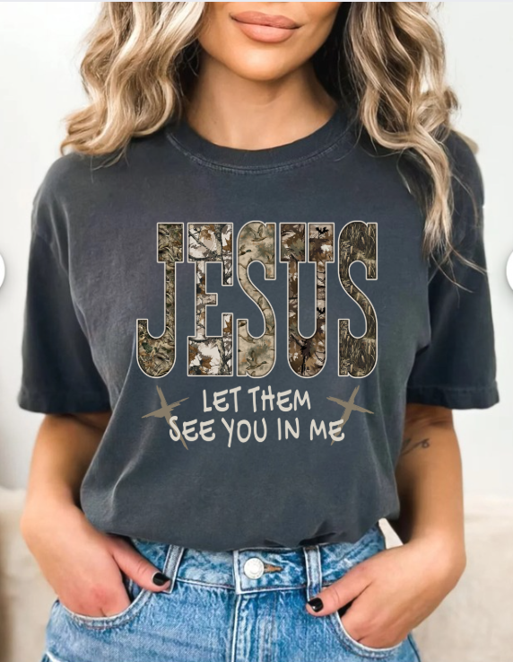 Person wearing a black t-shirt with 'Jesus Let Them See You In Me' text design.